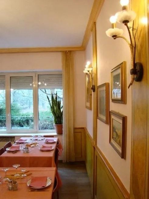Saletta con tovaglie rosa, applique e quadri alle pareti